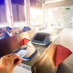 Selective focus to hand of passenger using smart card to open automatic gate machine at sky train station. Modern automatic ticket. Access control passenger of transportation concept.