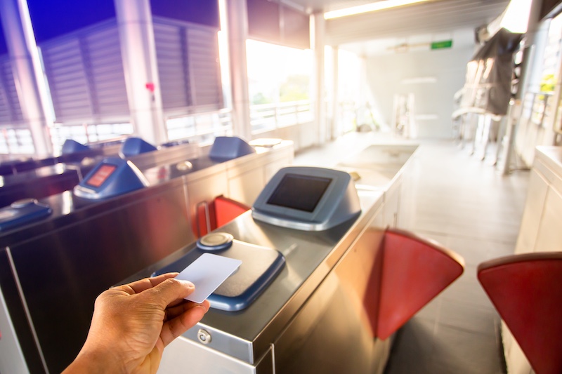 Selective focus to hand of passenger using smart card to open automatic gate machine at sky train station. Modern automatic ticket. Access control passenger of transportation concept.