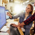 Young Caucasian colleagues working on computer in a warehouse