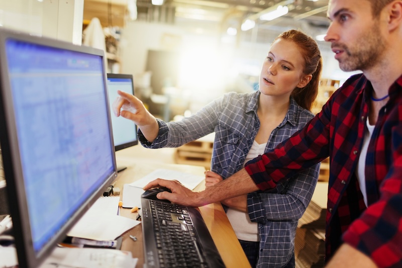 Young Caucasian colleagues working on computer in a warehouse