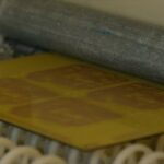 Organic and Printed Electronics Association’s Survey Industrial roller pressing flexible printed circuit board during automated production process in modern electronics factory, showcasing advanced manufacturing technology