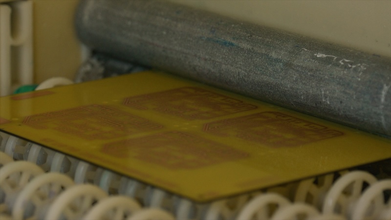 Organic and Printed Electronics Association’s Survey Industrial roller pressing flexible printed circuit board during automated production process in modern electronics factory, showcasing advanced manufacturing technology