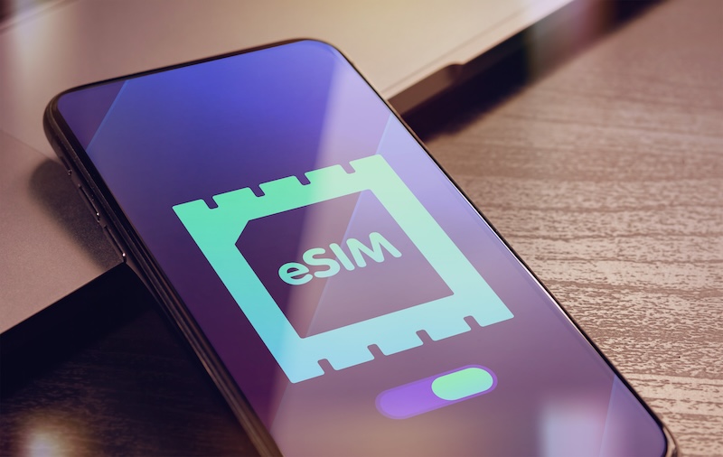 Comprion Giesecke+Devrient eSim - Embedded SIM technology concept with smartphone very close lying on a wooden table with esim icon on the screen.